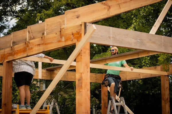 man and woman constructing a building using lumber