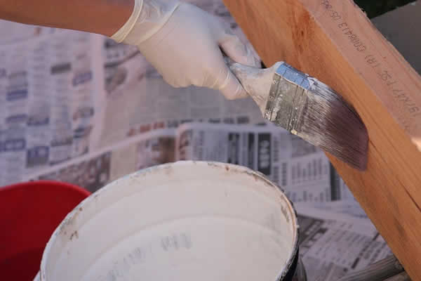 bucket of white paint, hand with white glove, painting wood