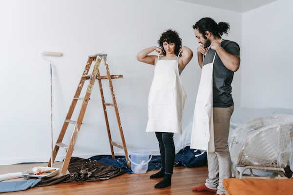 man and woman putting on white aprons for painting