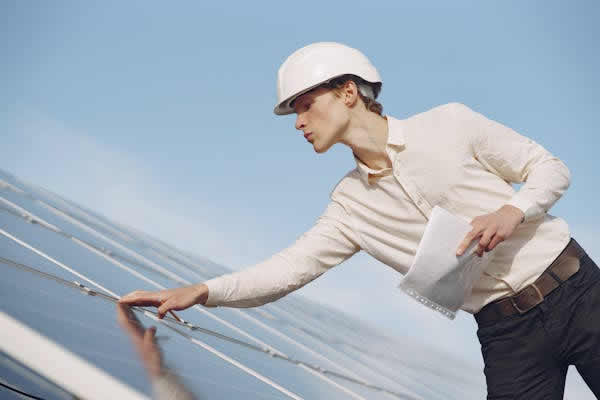 man with white hard hat inspecting a solar panel