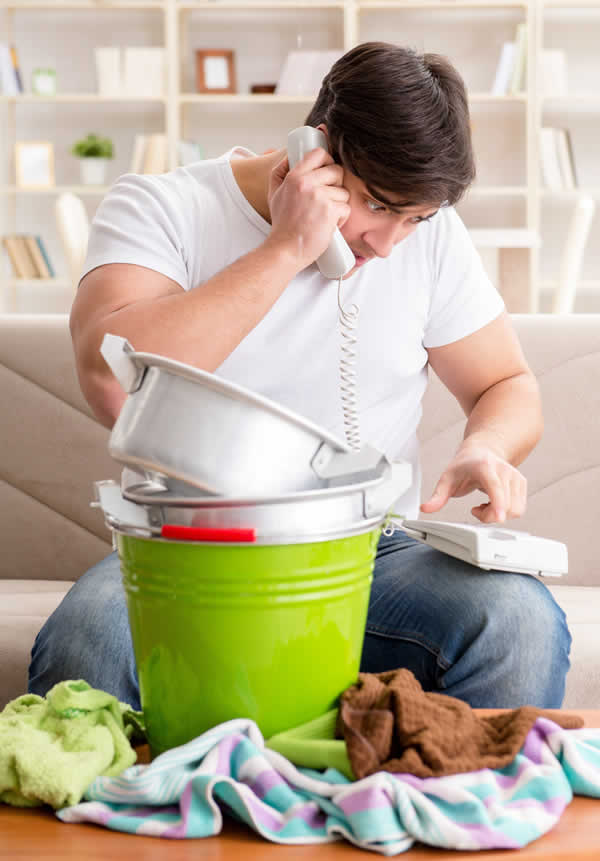 man sitting on floor on phone with buckets and towels