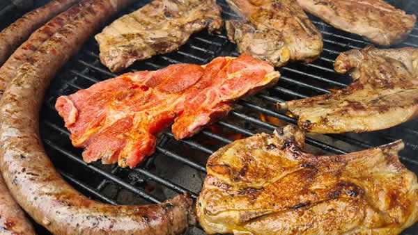barbeque grill covered with meat being cooked