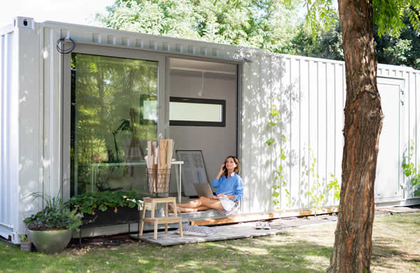 container house with woman sitting on floor with sliding glass doors