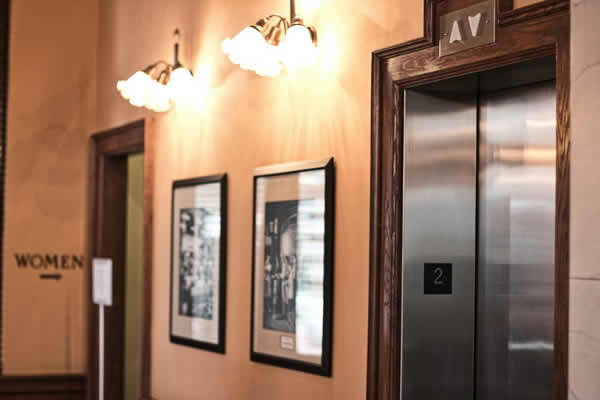 old style building hallway with elevator door, wall sconces and pictures