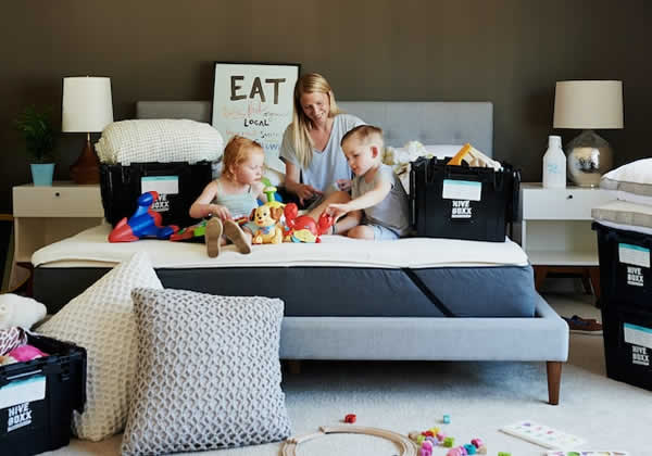 woman and children sitting on bed with moving boxes