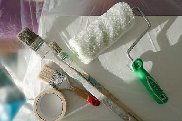 paint brushes and a roller on a drop cloth