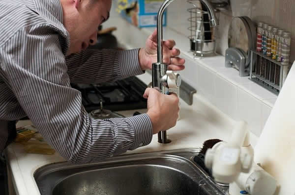 plumber fixing kitchen faucet