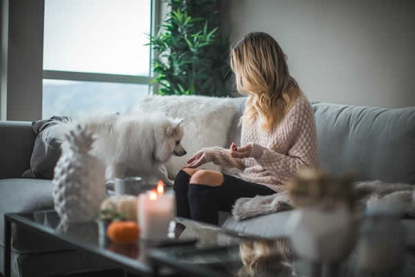 woman sitting on sofa with white dog