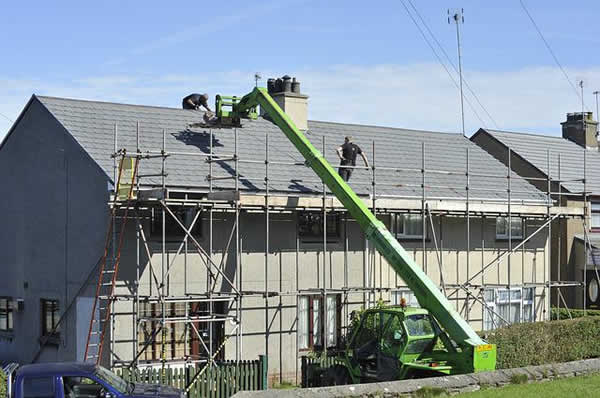 roofers repairing a roof with a lift and scaffolding