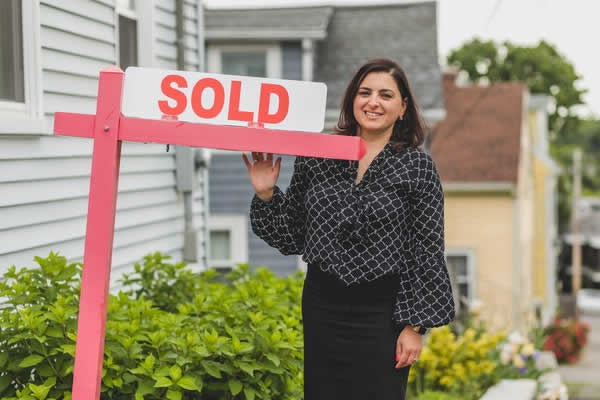 woman standing beside sold sign