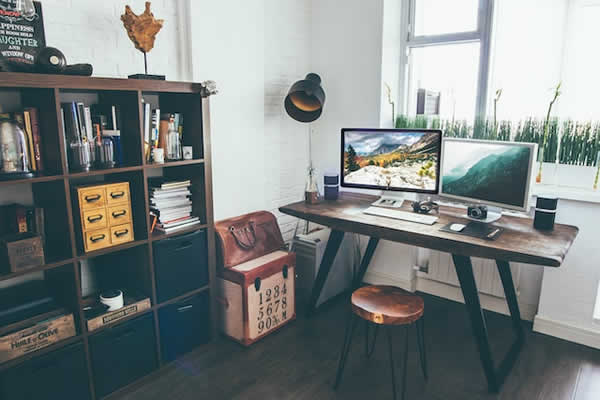 desk with computer screens and bookcase