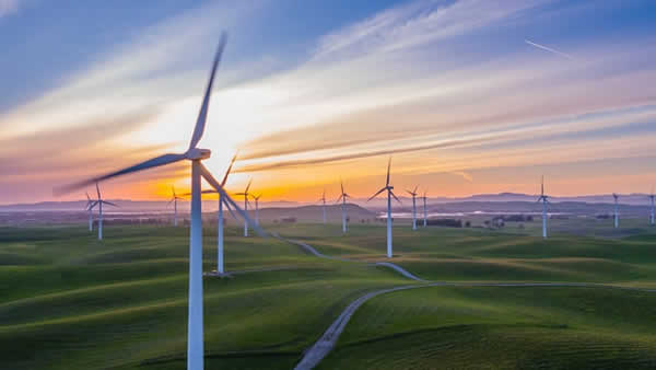 sun rising over a large wind farm
