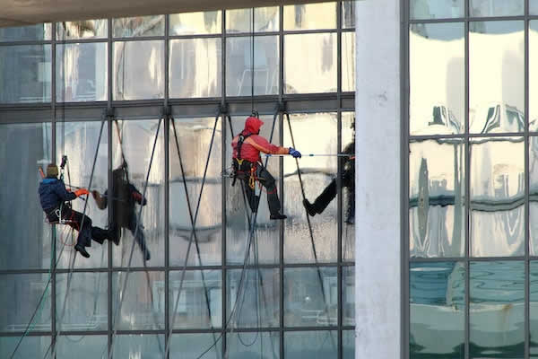 4 window washers hanging from ropes on tall building