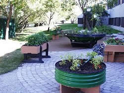 A variety of raised flower beds, all with raised bottoms. In the foreground a piece of 3 foot diameter corrugated galvanized pipe is used to create the garden bed.