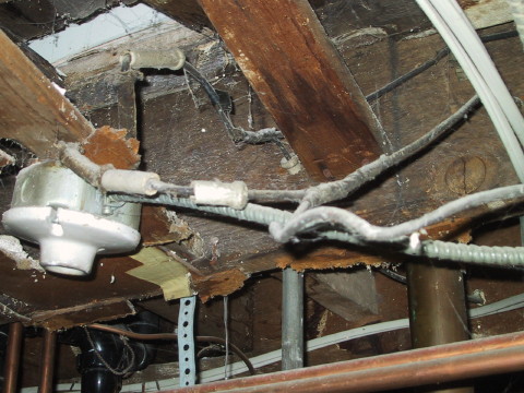 A combination of knob and tube wiring, armored cable and 14-2 some inside an electrical junction box, others spliced using tape.