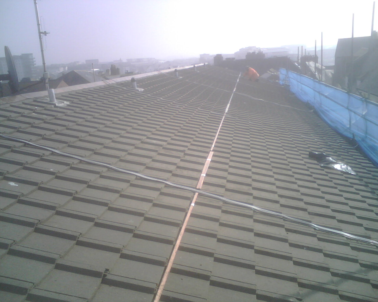 Image of the actual installation of a copper bar for moss control on a roof.