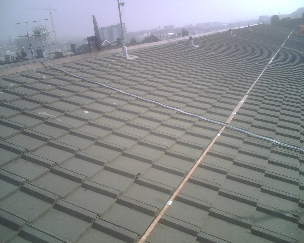 Image of the actual installation of a copper bar for moss control on a roof.