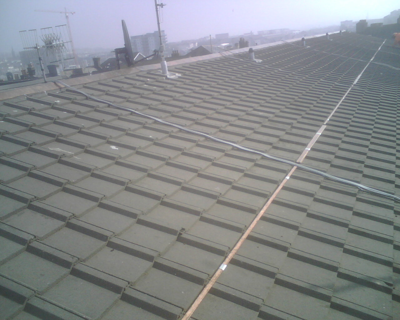 Image of the actual installation of a copper bar for moss control on a roof.